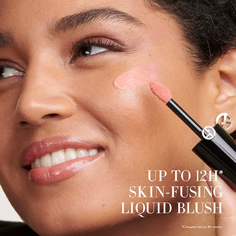 Image 1 - Close-up of a woman applying liquid blush to her cheek with an applicator, with the text UP TO 12H* SKIN-FUSING LIQUID BLUSH *Consumer test on 84 women. Image 2 - A close-up of Sadie Sink with red hair and blue eyes looking to the side, with the text SADIE SINK WEARS SHADE 50.5 Image 3 - Collage shows three women holding or applying Giorgio Armani makeup products, with product swatches and descriptions including fluid sheer glow enhancer GIORGIO ARMANI, luminous silk cheek tint GIORGIO ARMANI, FLUID SHEER Sheer liquid multi-use dewy finish, GLOW BLUSH Buildable powder blurs texture luminous finish, and CHEEK TINT Longwear liquid effortless blend natural finish. Image 4 - Two Giorgio Armani liquid cheek tint bottles and applicators, one matte and one shimmery, are shown with the text CHEEK TINT luminous silk cheek tint encre a joues GIORGIO ARMANI An effortless natural-looking liquid blush, rich in pigment that lasts up to 12 hours. CHEEK TINT SHINE luminous silk cheek tint shine encre a joues nacrée GIORGIO ARMANI A pearlescent liquid blush with 12-hour wear, lightweight blendability and a luminous finish.