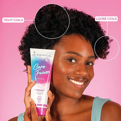 Image 1 - A woman smiles while holding a tube of Care Fusion co-wash in front of a pink background, with circles highlighting tight coils and loose coils in her hair. Les secrets de Loly is printed on the product.
Image 2 - A tube of Care Fusion co-wash product is centered on a pink background with bubbles, and the visible text states 2-IN-1 CLEANSE & CARE, Nettoie en douceur, and 80% HYDRATED AND NOURISHED HAIR*.
Image 3 - A tube of Care Fusion Co-Wash from Les secrets de Loly is displayed next to coconut halves, with text highlighting the benefits of babassu extract, lactic acid, and kaolin for hair care.
Image 4 - A person holds a tube of hair co-wash labeled Care Fusion against a pink background, with text pointing out features like Gently Cleanses, Nourishes, and Scalp Protection, while the tube also includes 250ml and Nettoie en douceur.